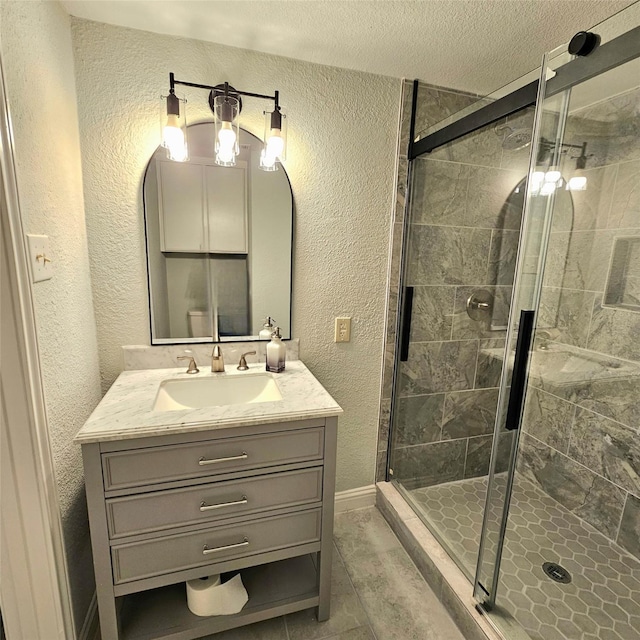 full bath featuring a stall shower, a textured wall, vanity, and a textured ceiling