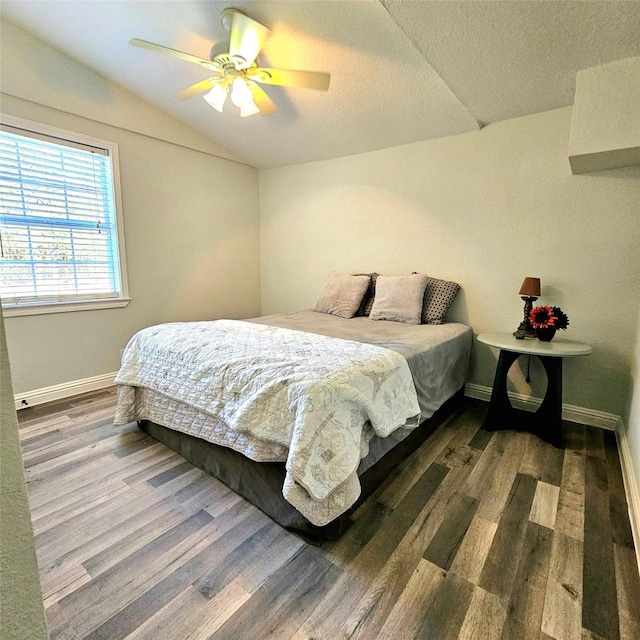 bedroom featuring vaulted ceiling, a textured ceiling, baseboards, and wood finished floors