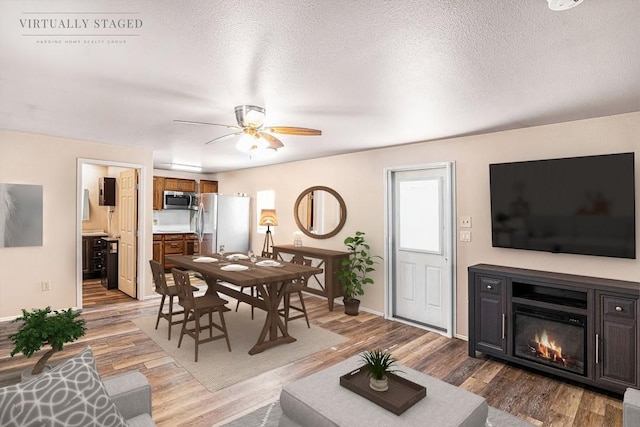 136 Clara Lee Ln, Springtown, TX 76082 - living room with light wood-style floors, a ceiling fan, baseboards, a glass covered fireplace, and a textured ceiling