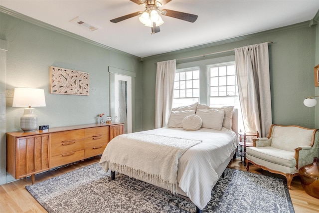 bedroom featuring ornamental molding, visible vents, light wood-style floors, and ceiling fan