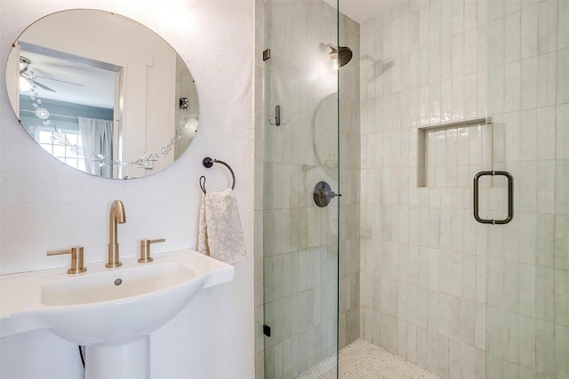 full bath featuring a textured wall, a stall shower, and a sink