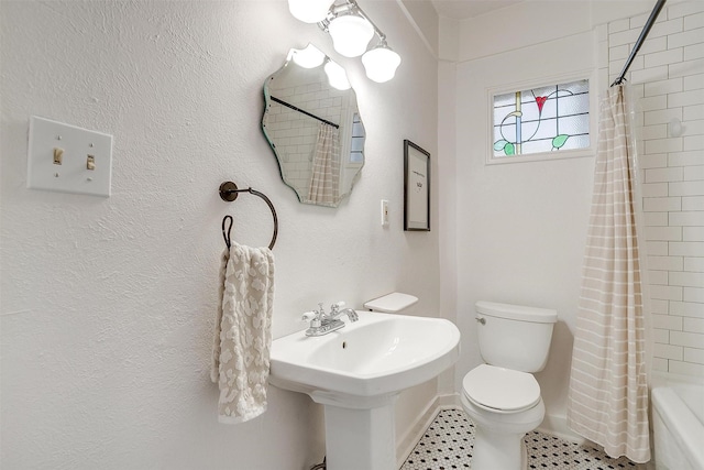 full bathroom with toilet, shower / tub combo, a sink, and a textured wall