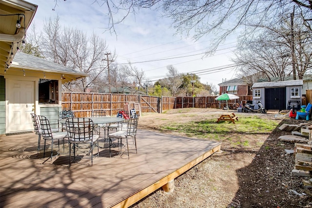 view of yard with outdoor dining area, a storage unit, a deck, a fenced backyard, and an outdoor structure