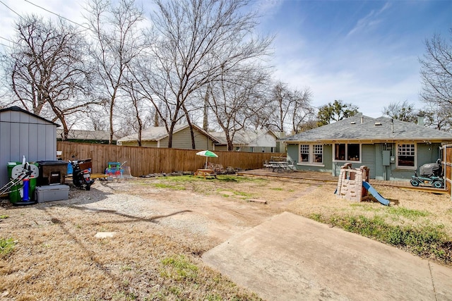 view of yard with an outbuilding, a playground, a patio, a shed, and a fenced backyard