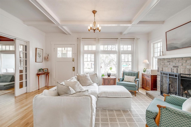 living area featuring coffered ceiling, light wood-style floors, a brick fireplace, beamed ceiling, and an inviting chandelier