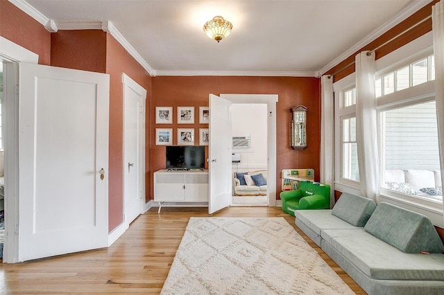 living area featuring crown molding, baseboards, a wealth of natural light, and light wood-style floors