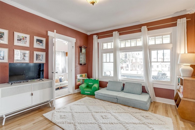 living area featuring ornamental molding, baseboards, and wood finished floors