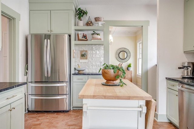 kitchen with light tile patterned floors, decorative backsplash, butcher block counters, a kitchen island, and stainless steel appliances