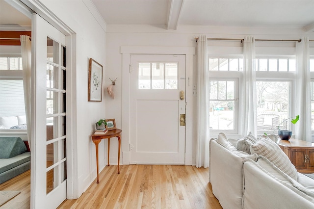 entrance foyer featuring crown molding, french doors, beamed ceiling, and light wood finished floors