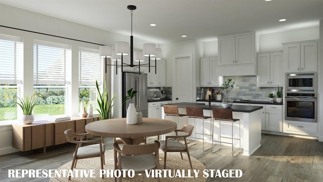 kitchen featuring dark countertops, plenty of natural light, stainless steel appliances, and wood finished floors