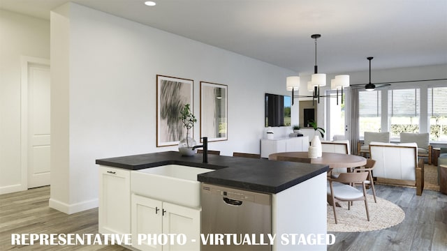 kitchen featuring dark countertops, open floor plan, dishwasher, and a sink