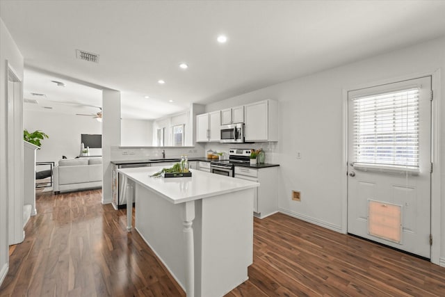 kitchen with stainless steel appliances, backsplash, visible vents, and dark wood finished floors