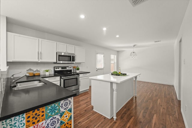 kitchen with visible vents, a sink, stainless steel appliances, white cabinets, and dark wood-style flooring