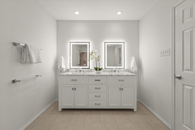 bathroom featuring double vanity, tile patterned flooring, baseboards, and a sink