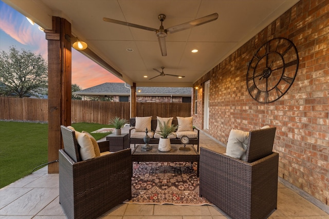 patio terrace at dusk with a yard, outdoor lounge area, a fenced backyard, and a ceiling fan