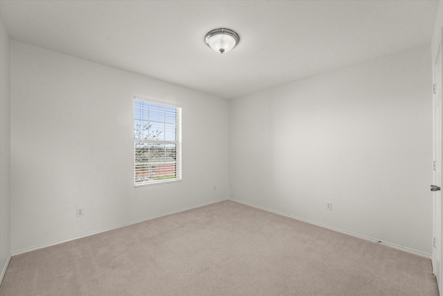 unfurnished room with light colored carpet and baseboards