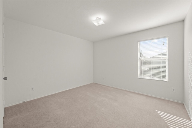 empty room featuring baseboards and light colored carpet