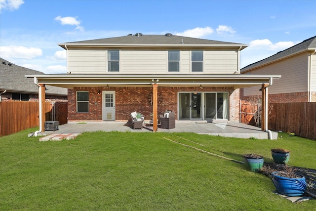 rear view of property featuring a patio, a lawn, a fenced backyard, and brick siding