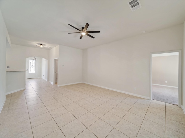 spare room featuring baseboards, visible vents, arched walkways, a ceiling fan, and light tile patterned flooring