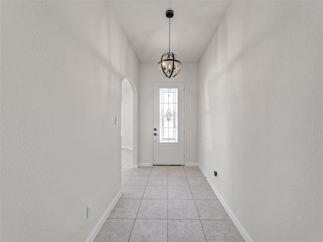 foyer entrance featuring arched walkways, an inviting chandelier, baseboards, and light tile patterned floors