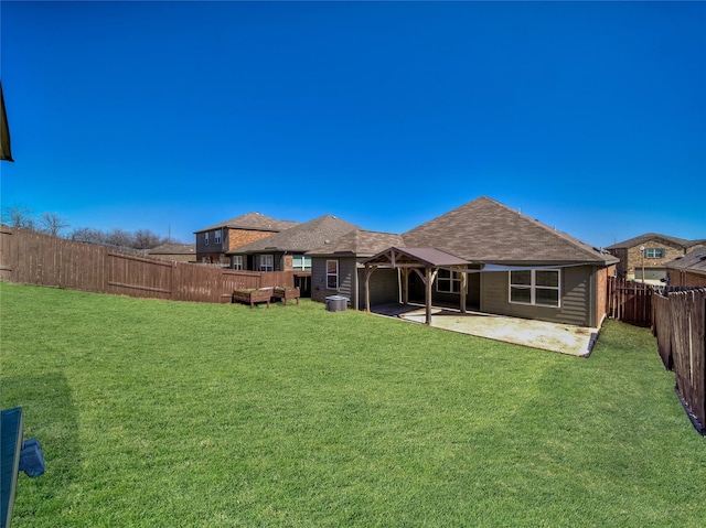 back of house featuring a shingled roof, a fenced backyard, a lawn, and a patio