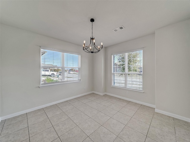 empty room with an inviting chandelier, plenty of natural light, visible vents, and baseboards