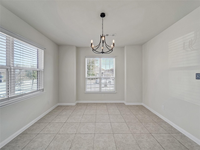 spare room featuring a chandelier, light tile patterned flooring, visible vents, and baseboards