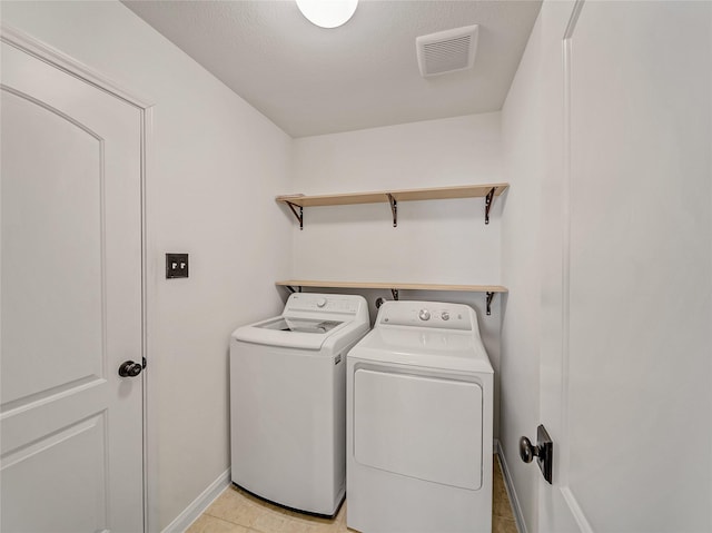 washroom featuring laundry area, washing machine and dryer, visible vents, and baseboards