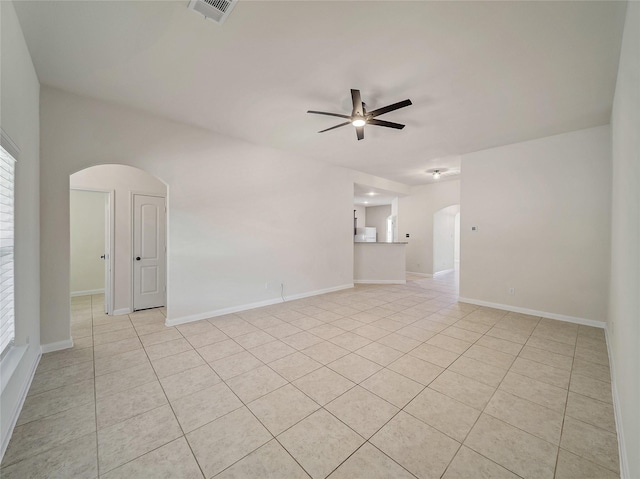 empty room featuring light tile patterned floors, visible vents, arched walkways, baseboards, and a ceiling fan