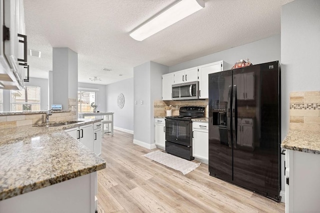 kitchen with decorative backsplash, light wood-style floors, black appliances, white cabinetry, and a sink