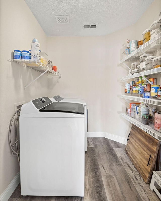 washroom with washer and clothes dryer, visible vents, a textured ceiling, wood finished floors, and laundry area