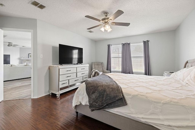 bedroom featuring ceiling fan, dark wood-style flooring, a textured ceiling, and visible vents