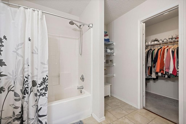 bathroom featuring a walk in closet, shower / bathtub combination with curtain, a textured ceiling, tile patterned flooring, and baseboards