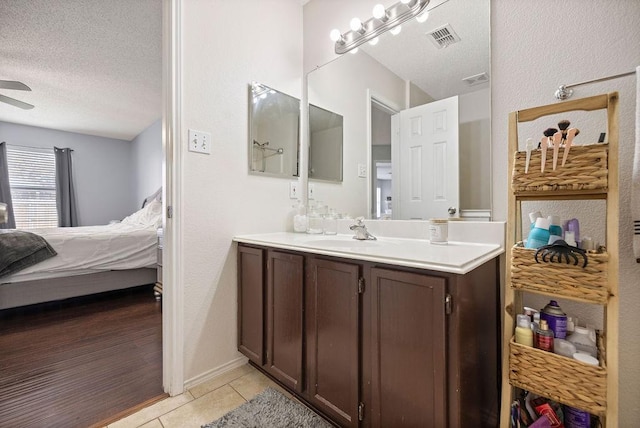 bathroom with visible vents, ensuite bath, tile patterned flooring, a textured ceiling, and vanity