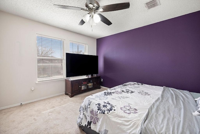 carpeted bedroom featuring a ceiling fan, visible vents, a textured ceiling, and baseboards