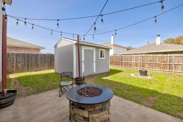 view of patio / terrace featuring an outbuilding, a fenced backyard, a fire pit, and a storage shed