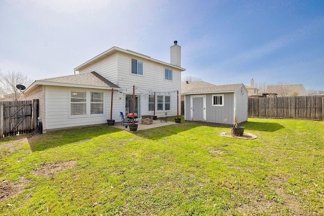 back of property featuring a yard, a fenced backyard, an outbuilding, and a patio