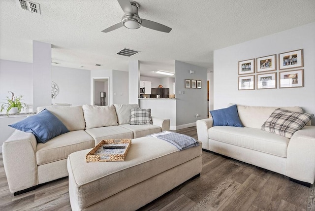 living room featuring visible vents, a textured ceiling, and wood finished floors