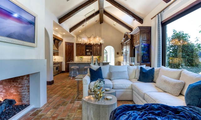 living area with arched walkways, beamed ceiling, brick floor, and plenty of natural light