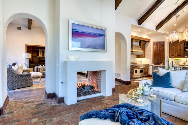 living area with arched walkways, brick floor, a multi sided fireplace, and visible vents