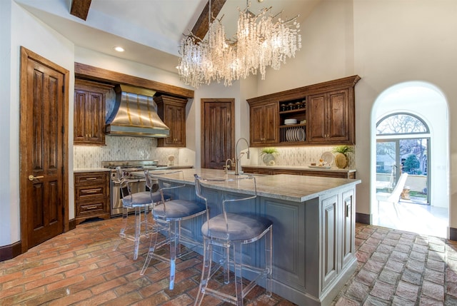 kitchen with wall chimney exhaust hood, decorative backsplash, open shelves, and double oven range