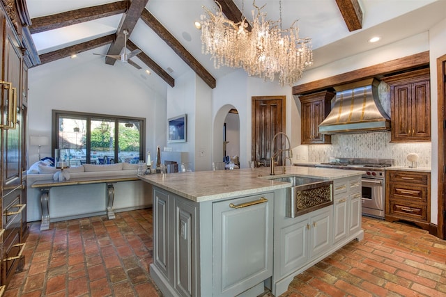 kitchen with arched walkways, open floor plan, high vaulted ceiling, premium range hood, and high end range