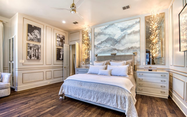 bedroom featuring ceiling fan, dark wood-type flooring, visible vents, and a decorative wall