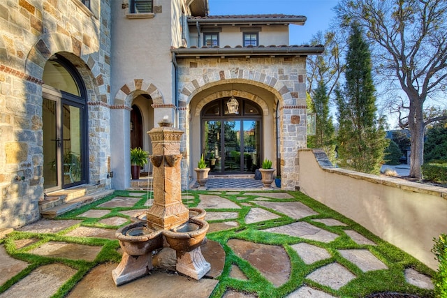 doorway to property with stone siding, french doors, and stucco siding