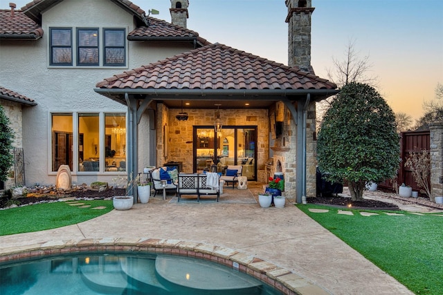 back of house with a chimney, a patio area, a tile roof, and stucco siding