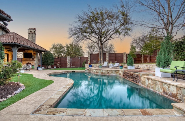 view of swimming pool with a fenced in pool, a patio area, an outdoor stone fireplace, and a fenced backyard