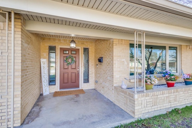 view of exterior entry with brick siding and a porch