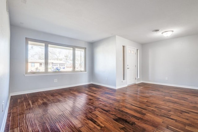 spare room featuring dark wood-style floors and baseboards