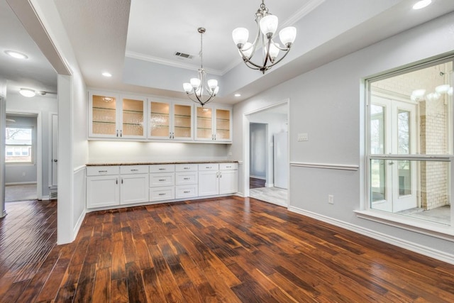 kitchen featuring visible vents, glass insert cabinets, ornamental molding, a notable chandelier, and white cabinets