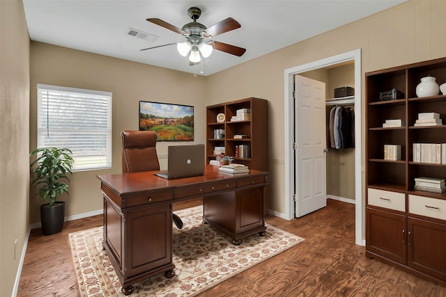 home office with baseboards, ceiling fan, visible vents, and dark wood-style flooring